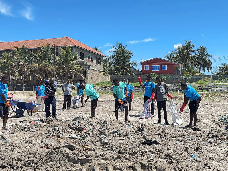 Group of people raking and bagging waste from sandy mounds