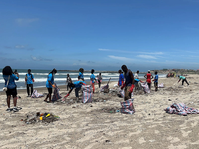 Volunteers filling striped collection bags on a sandy shoreline