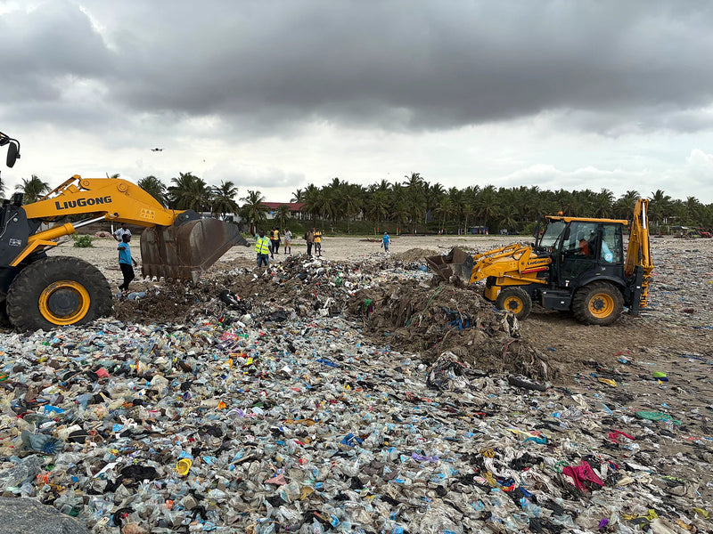 Two yellow machines working a wide stretch of plastic waste on a beach