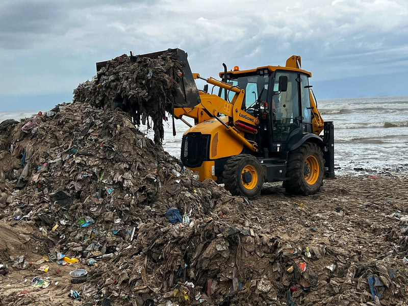 Yellow loader dumping wet waste onto a pile at the ocean’s edge