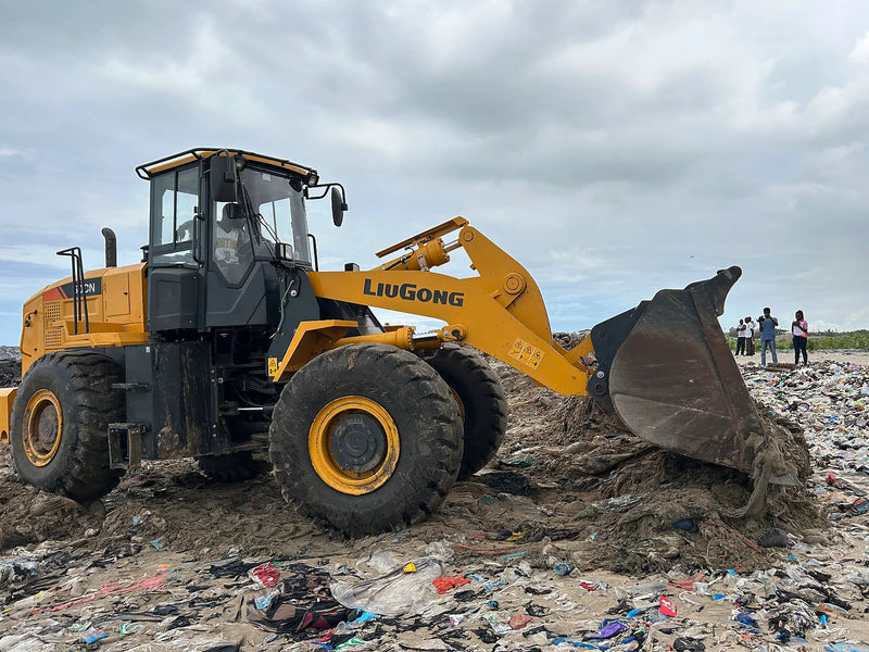 Yellow loader scooping tangled waste from a debris-covered beach