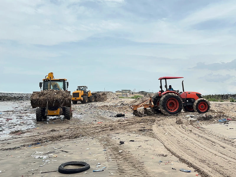 Yellow loader and red tractor working a sandy shoreline together