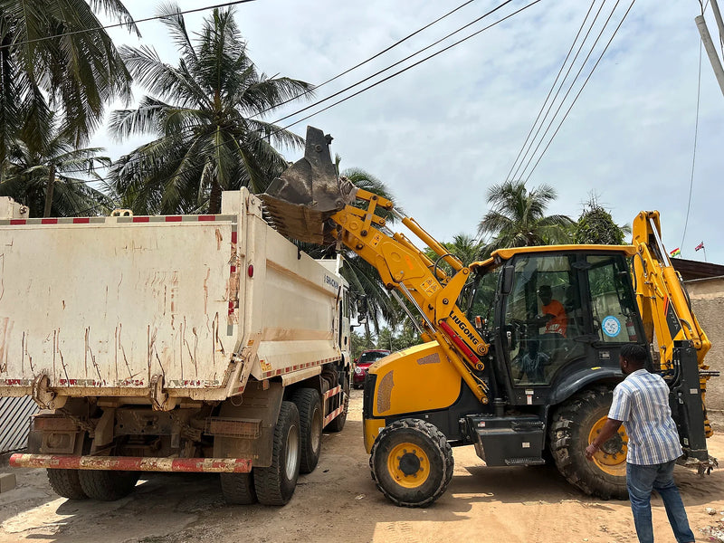 Yellow loader emptying material into a white dump truck