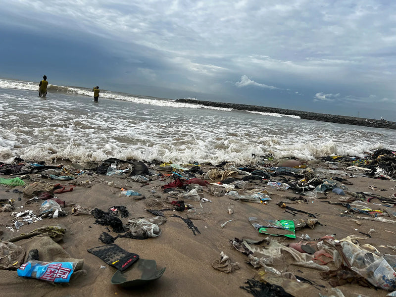 Close view of plastic bags and trash at the waterline as waves break