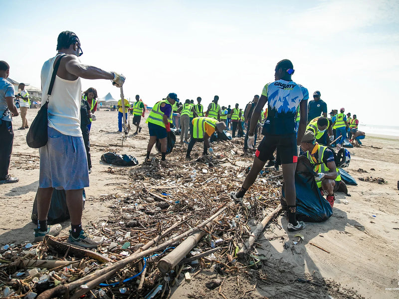 Many people working a long line of driftwood and plastic waste on a beach