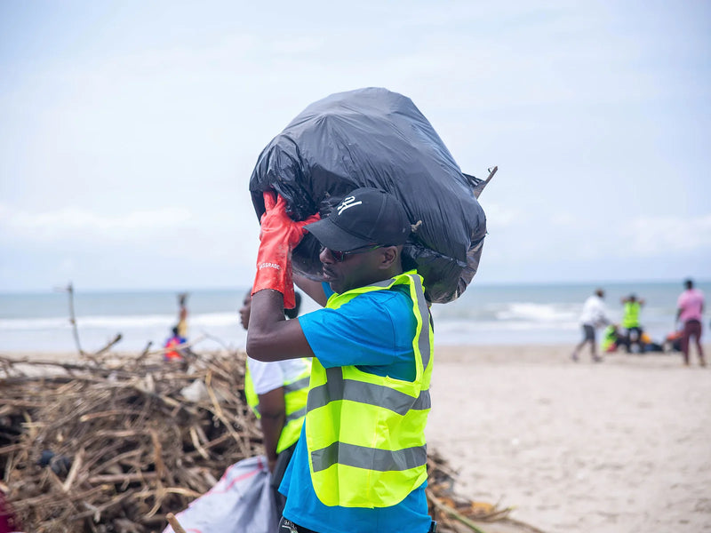 Person in a yellow vest carrying a full black bag on one shoulder